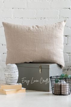 a gray trunk sitting on top of a table next to a pillow and some books