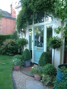 a blue door surrounded by potted plants in front of a white house with green trim