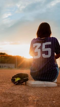 a person sitting on the ground with a baseball mitt in front of them,