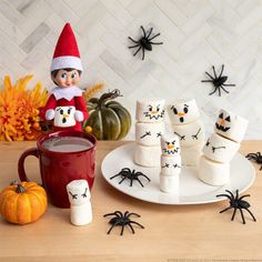 an elf is sitting on a plate with marshmallows and spider webs