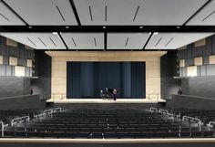 an empty auditorium with two people sitting on the stage