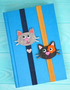 a blue book with two felt cats on the front and one cat on the back