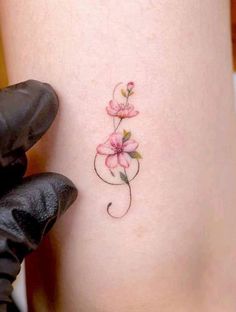 a small pink flower tattoo on the side of a woman's right leg,