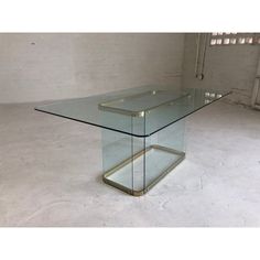 a glass and metal table in the middle of an empty room with no one around it