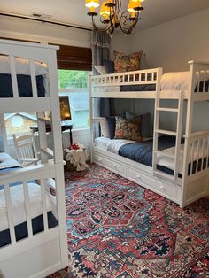 a room with bunk beds, rugs and chandelier hanging from the ceiling