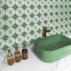 a green sink sitting next to two soap dispensers