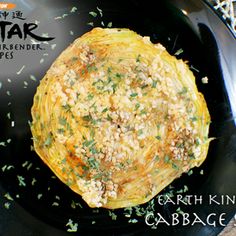 a black plate topped with an artichoke on top of a table