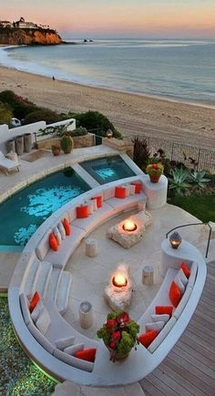 an outdoor hot tub next to the beach at dusk with candles lit up on it