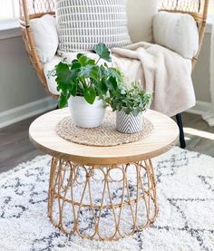 two potted plants sitting on top of a wooden table in front of a chair