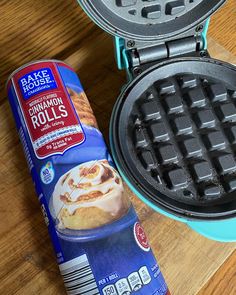 a waffle iron next to a container of cinnamon rolls