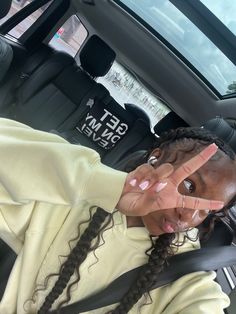 a woman sitting in the back seat of a car making a peace sign with her hands