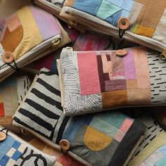 several multicolored patchwork purses stacked on top of each other with zipper closures