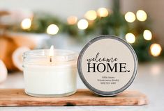 a candle sitting on top of a cutting board next to a jar of candles with the words welcome home