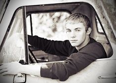 a young man sitting in the drivers seat of a pickup truck looking out the window