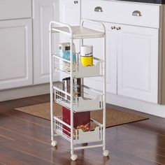 a kitchen with white cabinets and wooden flooring next to a counter top on wheels