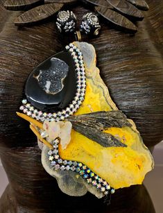 I love the uniqueness of this piece! A high-grade and now rare slab of bumblebee jasper hosts a black druzy agate, black kyanite spears, an angel aura quartz cluster, two shards of a yellow quartz and black aurora borealis rhinestones. The pendant measures 5.5" x 4" and is flanked by two Polynesian black and silver designer beads. A black jasper pointed oval beaded statement necklace supports the pendant, with the back being finished with faceted crystals and rhinestone rondelles. Adjusts from 2 Unique Onyx Gemstone Necklace, Handmade Onyx Necklaces, Handmade Onyx Necklaces With Unique Style, Unique Handmade Onyx Necklaces, Handmade Onyx Necklace With Unique Style, Rocker Chic Accessories, Black Aurora, Black Kyanite, Black Jasper