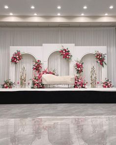 a stage set up for a wedding ceremony with flowers and candles on the sidelines