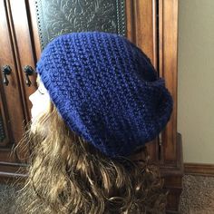 a woman's head wearing a blue knitted beanie hat on top of her head