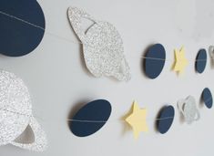 the space themed garland is hanging on the wall with paper stars and moon shapes attached to it