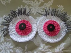 two crocheted eyeballs with black and pink centers sitting on a floral background