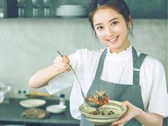 a woman in an apron is holding a bowl with food on it and a fork