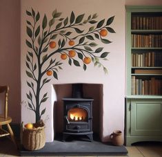 an orange tree painted on the wall next to a fireplace