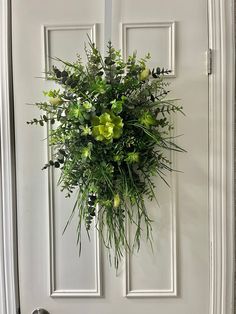 a white door with green flowers hanging from it's side