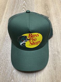 This Bass Pro Shops trucker hat is perfect for any outdoor enthusiast. The hat features a dark green color with the Bass Pro Shops logo embroidered on the front. The adjustable strap ensures a perfect fit for anyone, and the mesh back allows for breathability in all seasons. Made from lightweight polyester fabric, this hat is perfect for casual occasions like fishing or hunting. Its solid pattern and unisex design make it a great addition to any wardrobe. Get your hands on this hat today and sho Bass Pro Shop Hat Outfit, Bass Pro Shop Hats, Brown Bass Pro Shop Hat, Brown Snapback Fishing Hat, Bass Pro Shop, Mens Trucker Hat, Mesh Cap, Shop Logo, Unisex Design