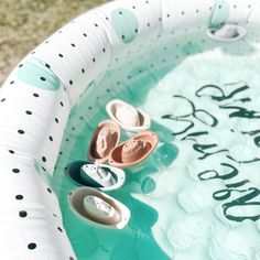 two pairs of baby shoes are sitting in an inflatable pool with the words happy birthday written on it