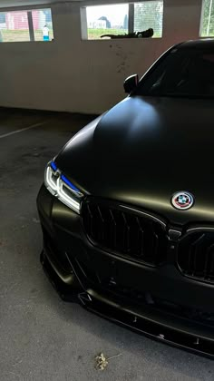 the front end of a black car parked in a garage