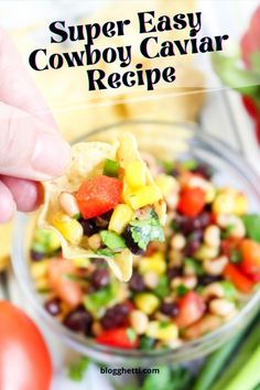 a hand holding a tortilla chip with black eyed peas, corn and tomatoes