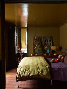 a bed sitting in a bedroom next to a painting on the wall and wooden floor