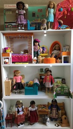 a doll house filled with lots of dolls on top of white bookshelves next to each other