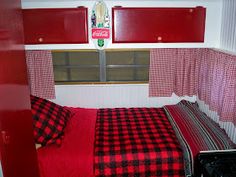 a red and black checkered bedspread in a small room with coca - cola sign on the window