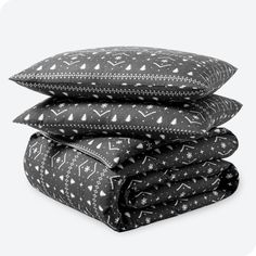 three pillows stacked on top of each other in black and white patterns, with one pillow folded up to the side