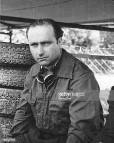 an old black and white photo of a man sitting in front of stacks of tires