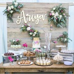 the dessert table is set up with flowers and cookies on it, along with an array of sweets