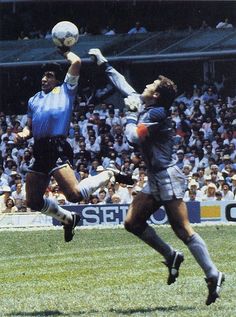 two soccer players jump to head the ball in front of an audience at a sporting event