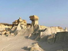 some very pretty formations in the desert with blue sky behind them and white sand on the ground