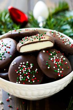 a white bowl filled with chocolate covered cookies and sprinkles on top of a wooden table