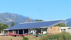 a house with a solar panel on the roof and mountains in the backround