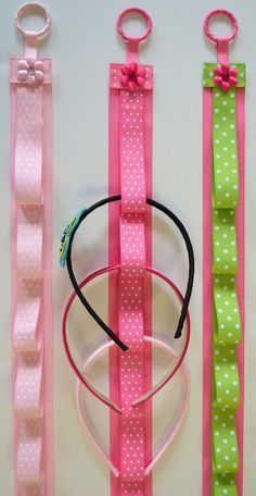 three pink and green hair ties, one with a bow on the end are lined up next to each other