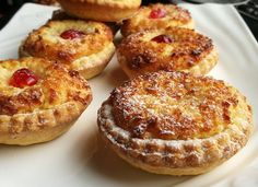 several pastries on a white plate with powdered sugar and cherries in the middle