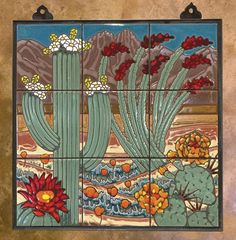 a decorative tile with flowers and cactuses on it's side, hanging from the wall