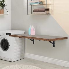 a washer sitting next to a dryer in a room with a shelf on the wall