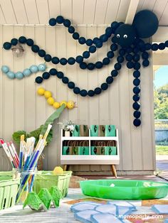 an octopus made out of balloons is on the wall next to some green bins