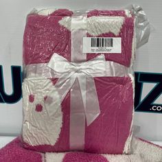 a pink and white blanket with a bow on it's side, wrapped in plastic