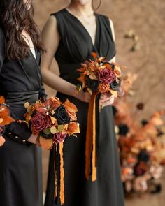 two bridesmaids in black dresses holding bouquets with orange and red flowers on them