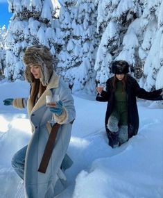 two women walking in the snow with drinks