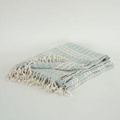 a light blue and white striped blanket folded on top of each other with fringes